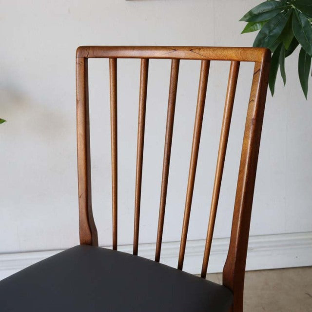 Vintage mid-century British teak dining chair with sharp backrest vertical slats and black upholstered seat.