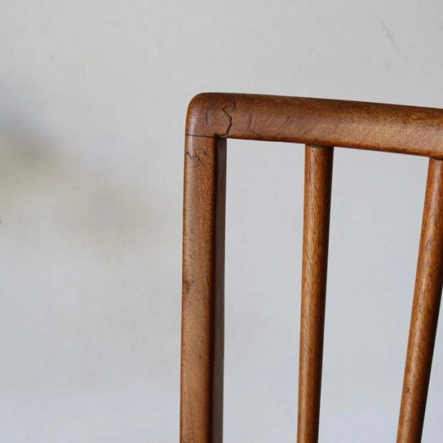 Vintage teak dining chair backrest with sharp, clean lines, British mid-century Denmark style, smooth wood grain visible.