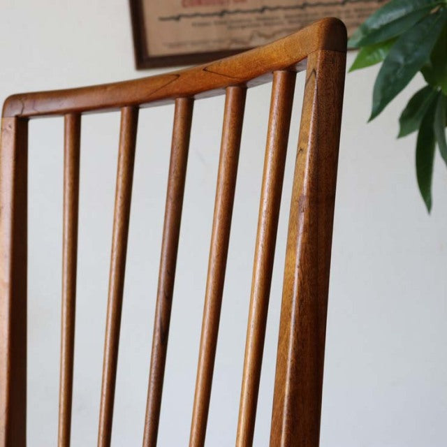 Vintage mid-century British teak dining chair back with slender vertical slats and smooth wood grain.