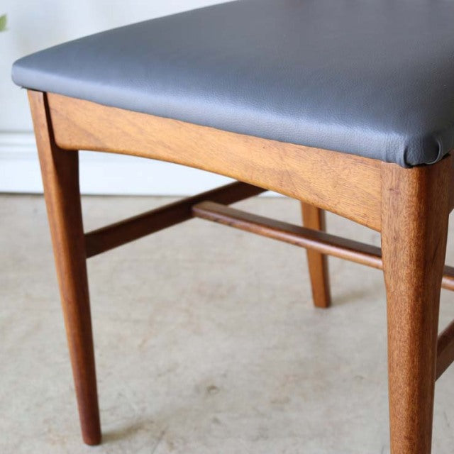 Vintage mid-century teak dining chair with smooth wood grain, sharp backrest, and gray upholstered seat, British Denmark.