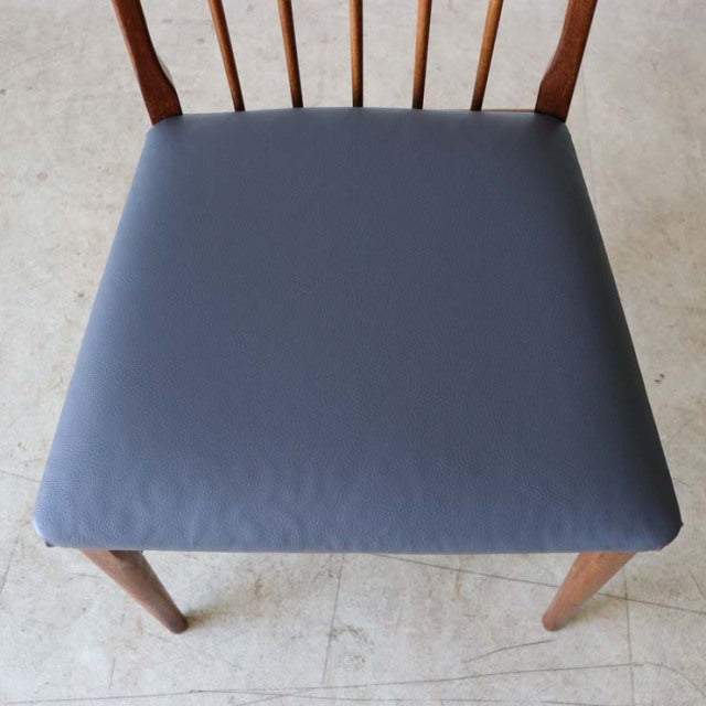 Vintage mid-century teak dining chair from Denmark with smooth navy upholstered seat and slender spindle backrest.
