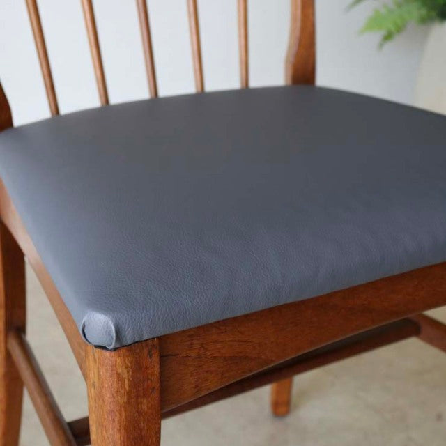 Vintage teak dining chair seat with smooth dark gray leather upholstery and sharp backrest, mid-century British Denmark.