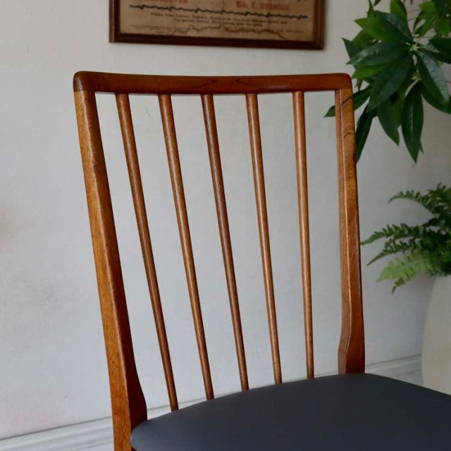 Mid-century British teak dining chair with slim vertical spindle back and black upholstered seat, vintage Danish design.