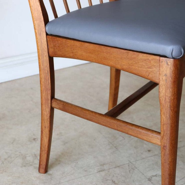 Vintage teak mid-century British dining chair with sleek sharp back and dark gray upholstered seat.