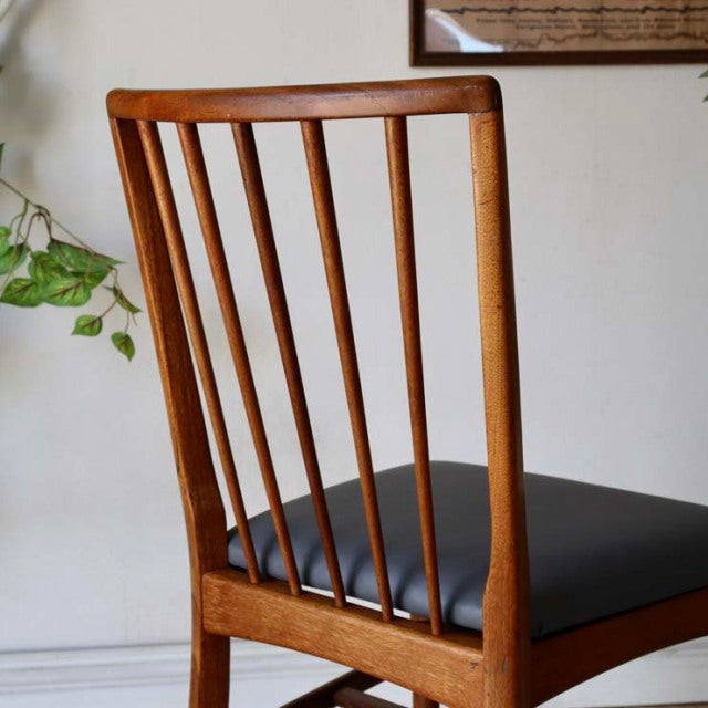 Vintage British mid-century teak dining chair with black upholstered seat and vertical slat backrest.