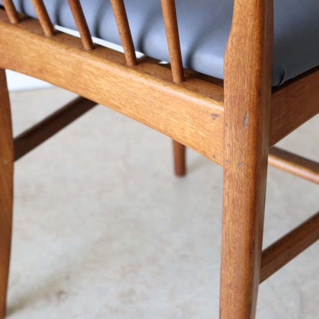 Close-up of vintage teak wood chair leg with visible grain, slim tapering Mid-century British design, Danish-inspired.
