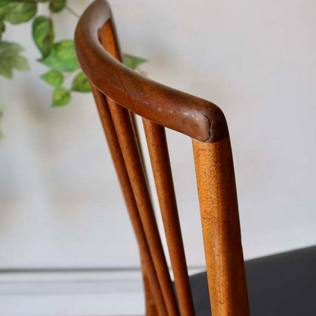 Mid-century British vintage teak dining chair back with smooth curved top rail and vertical slats, showing rich wood grain.