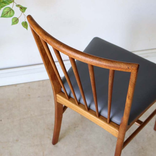 Vintage teak mid-century British dining chair with curved spindle back and black leather seat.