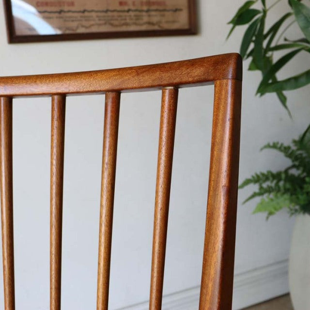 Mid-century British teak dining chair with sharp backrest and vertical slats, visible wood grain.