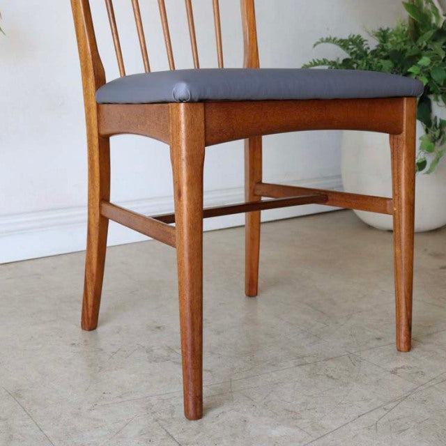 Vintage British mid-century teak dining chair with sharp backrest, gray upholstered seat, and tapered legs.