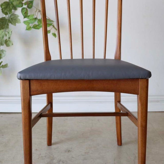 Vintage mid-century British teak dining chair with sharp back slats and black cushioned seat.