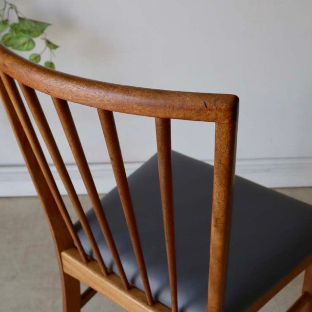 Vintage mid-century teak dining chair with British-Denmark design, featuring slender vertical back spindles and black.