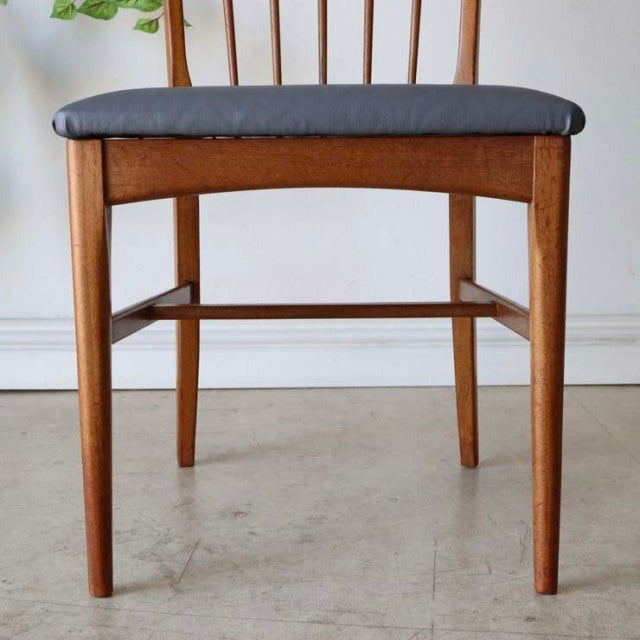 Vintage teak dining chair with mid-century British and Danish design, slender tapered legs, dark gray fabric seat, and.