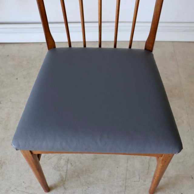 Vintage mid-century teak dining chair with sharp backrest spindles, blue upholstered seat, and tapered legs, British-Denmark .