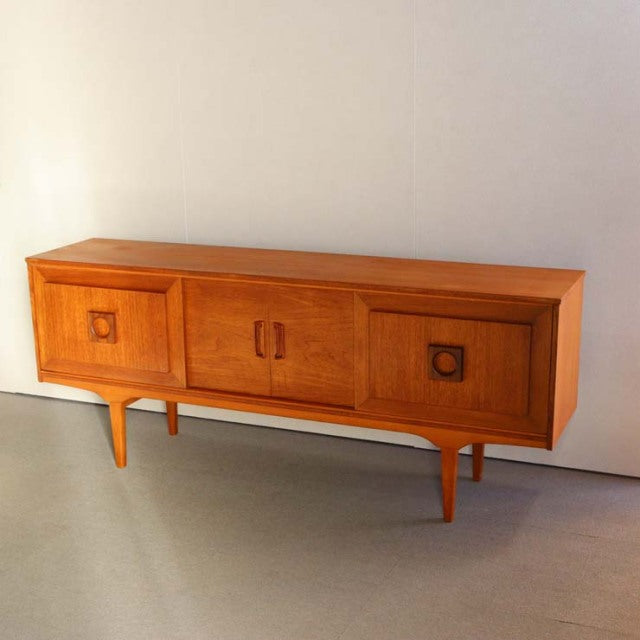 Mid-century British vintage teak sideboard with three doors, rich wood grain, and tapered legs.