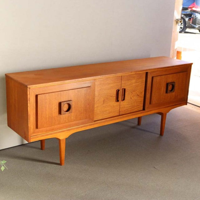 Mid-century British vintage teak sideboard with smooth grain, three cabinet doors, and tapered legs from Denmark style.