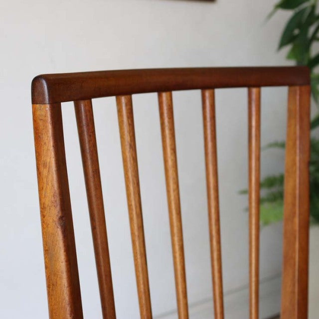 Mid-century vintage teak dining chair with British-Danish design, vertical slat back, warm wood grain, smooth rounded edges.