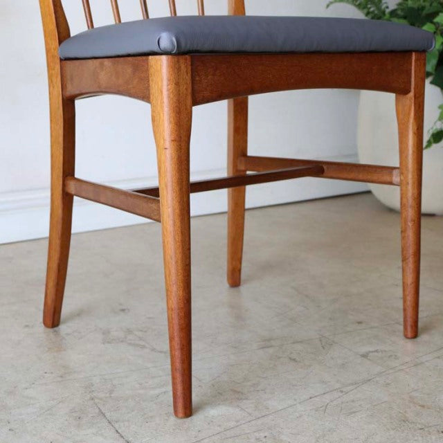 Vintage teak dining chair with sharp back, mid-century British design, smooth wood grain and tapered legs.