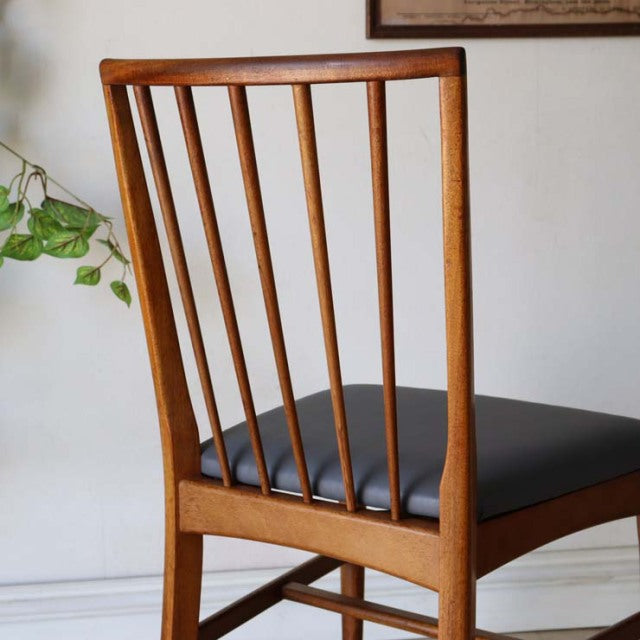 Vintage teak dining chair with slim vertical back slats, mid-century British design, black cushioned seat, clean lines, and.