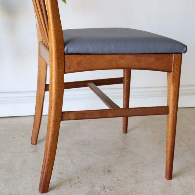 Vintage teak dining chair with sharp back design, mid-century British style, smooth wood grain, grey cushioned seat, slender .
