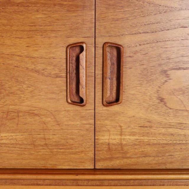 Vintage teak mid-century British sideboard doors with recessed wood handles and visible wood grain.