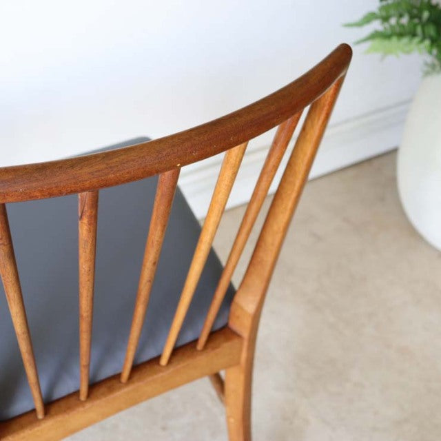 Vintage mid-century British teak dining chair with sharp backrest, vertical spindles, and smooth wood grain.