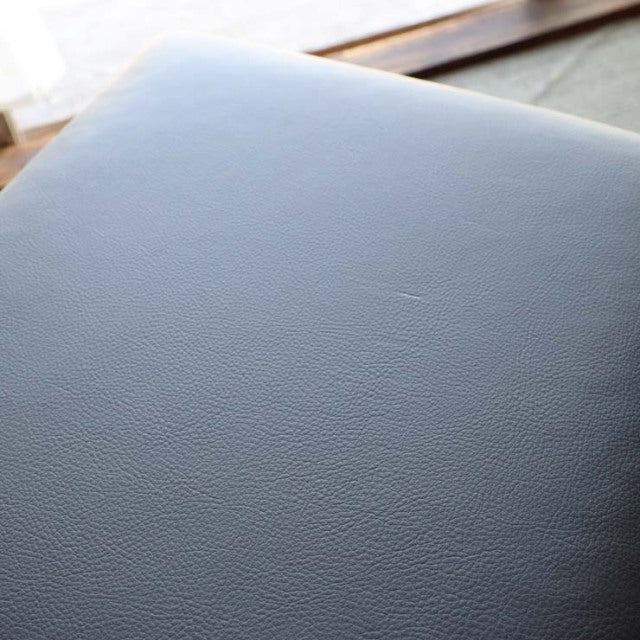 Close-up of black leather upholstered seat highlighting smooth texture and subtle grain of vintage teak frame from British.