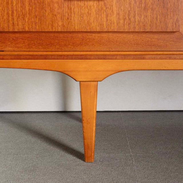 Close-up of vintage teak sideboard leg with mid-century British design and smooth wood grain finish.