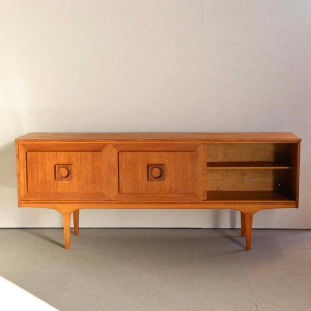 Mid-century vintage teak sideboard with British craftsmanship, featuring wood grain, circular recessed handles, tapered.