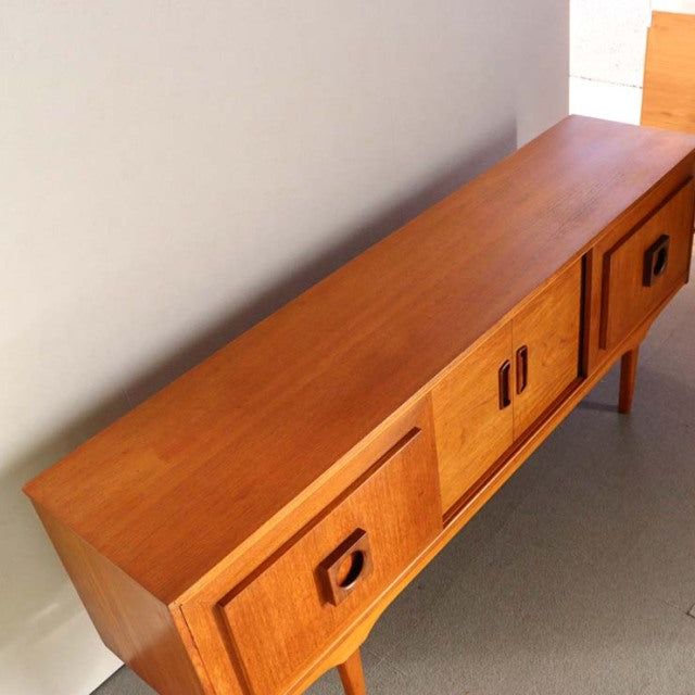 Mid-century vintage British teak sideboard with rich wood grain, clean lines, and square recessed handles.