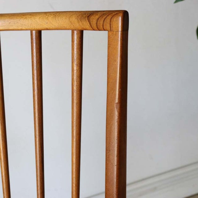 Mid-century vintage teak dining chair backrest with smooth wood grain and slender vertical spindles, British-Denmark style.