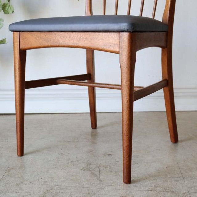 Mid-century British vintage teak dining chair with sharp square back and black upholstered seat, sleek tapered legs.