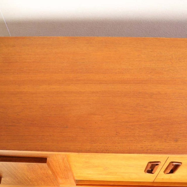Vintage teak mid-century British sideboard top surface showcasing smooth wood grain and warm honey tones.
