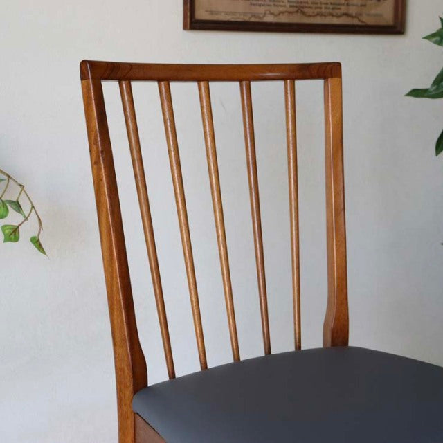 Vintage mid-century teak dining chair from British-Danish design, featuring slim vertical back spindles and a dark.
