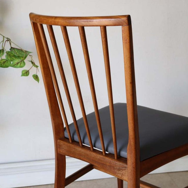Vintage mid-century teak dining chair with slim vertical spindles and black leather seat, British-Danish style.