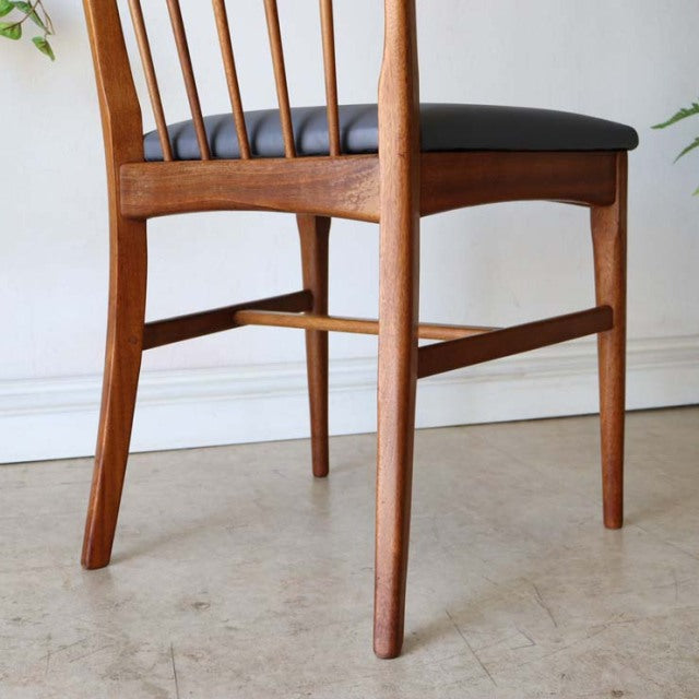Mid-century British vintage teak dining chair with sleek spindle back and black cushioned seat, Scandinavian design.