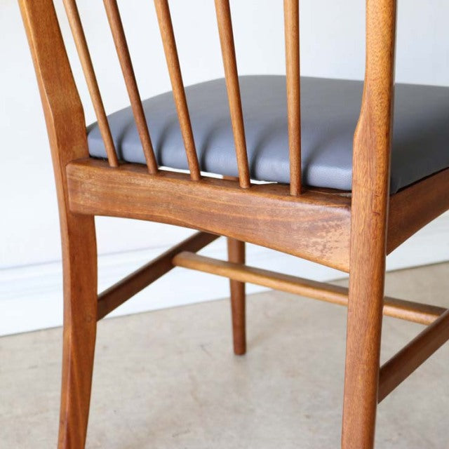 Mid-century vintage teak dining chair with slender spindle back, smooth wood grain, and black leather seat from.