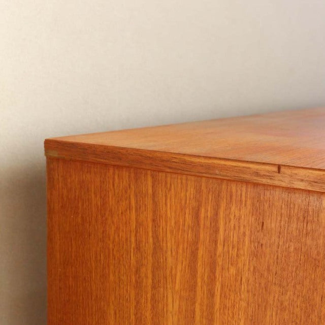 Vintage teak British mid-century sideboard corner with rich wood grain and smooth finish.