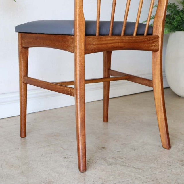 Vintage mid-century teak dining chair from Denmark with slender tapered legs and black cushioned seat.