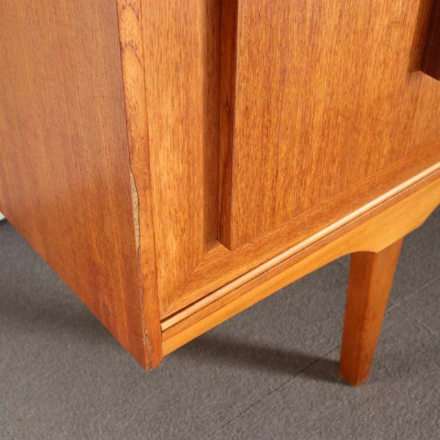 Vintage teak mid-century British sideboard leg with visible wood grain and clean lines against gray floor.