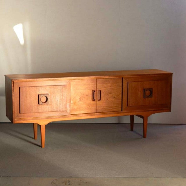 Mid-century British vintage teak sideboard with smooth wood grain, tapered legs, and square recessed handles.