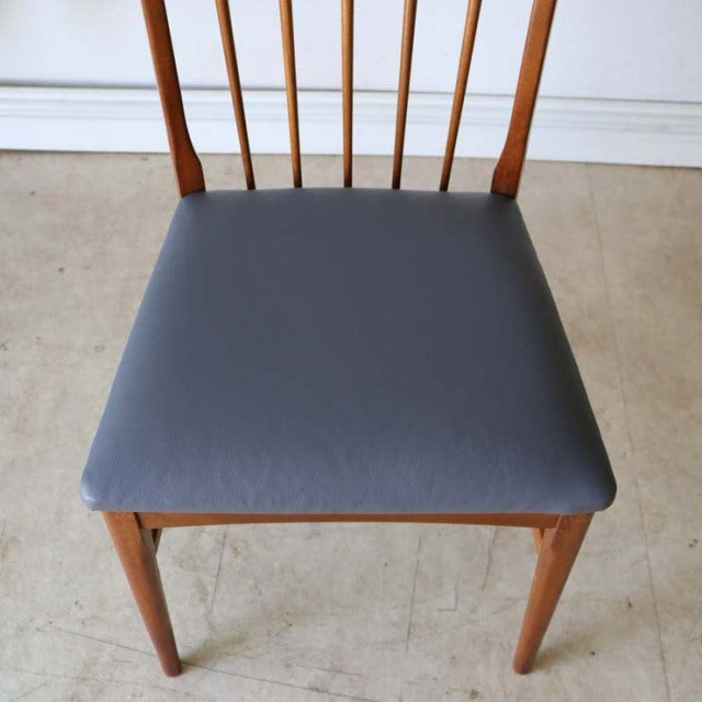 Vintage teak dining chair with sleek mid-century British design, slender spindle back and gray seat cushion, showcasing warm .
