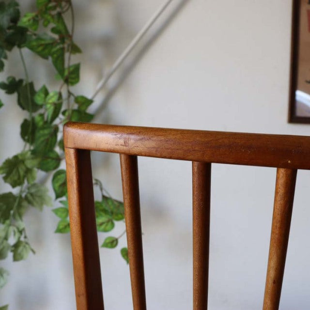 Mid-century British vintage teak dining chair with sharp backrest and vertical slats, smooth wooden grain finish.