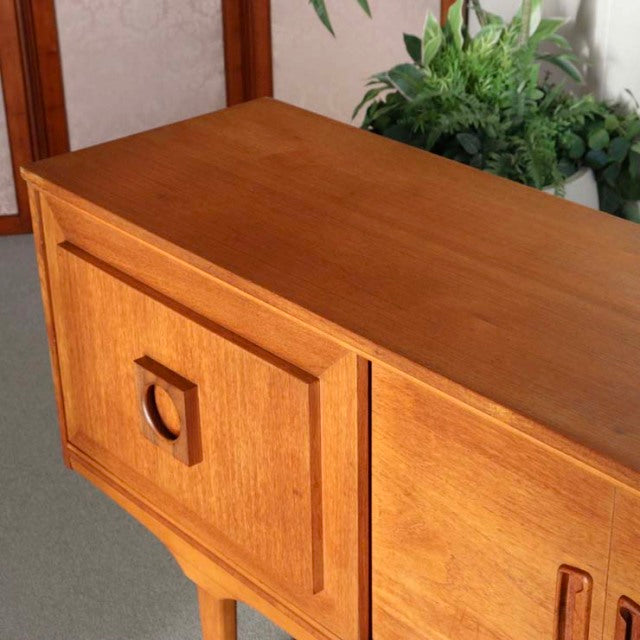 Vintage teak British mid-century sideboard with rich wood grain and tapered legs.