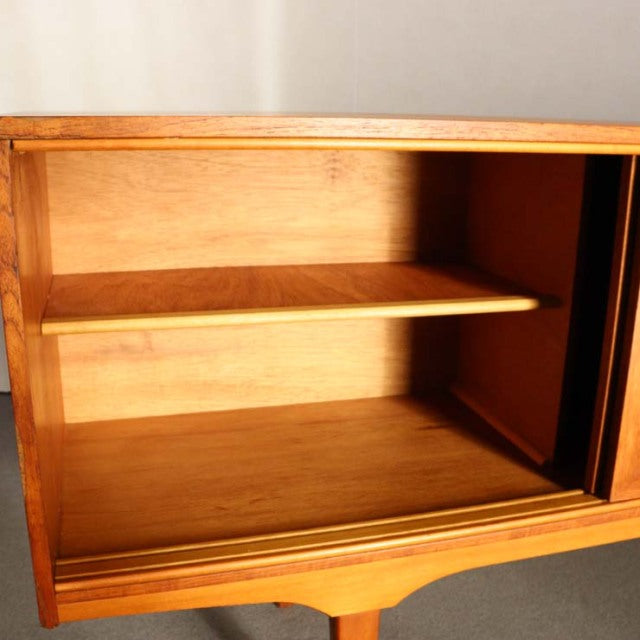 Vintage teak sideboard with British mid-century design, smooth wood grain, tapered legs, and a split-door panel revealing.