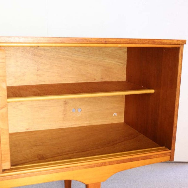 Mid-century British vintage teak sideboard with visible wood grain, open shelf, and simple clean lines.