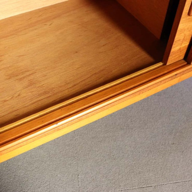 Close-up of vintage teak mid-century British sideboard interior showing warm wood grain and smooth finish.