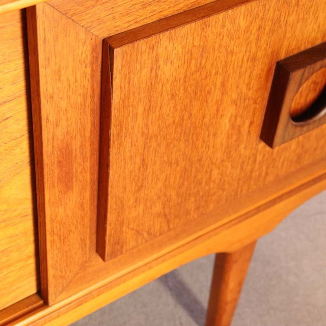 Mid-century British vintage teak sideboard corner showing rich wood grain, recessed panel, and tapered leg detail.