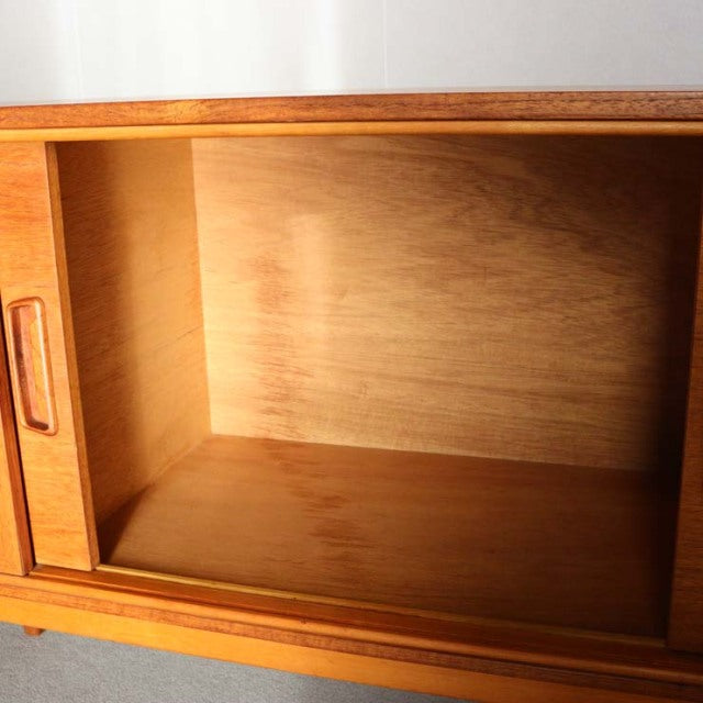Vintage teak mid-century British sideboard with rich wood grain and sliding door details, crafted in Denmark style.