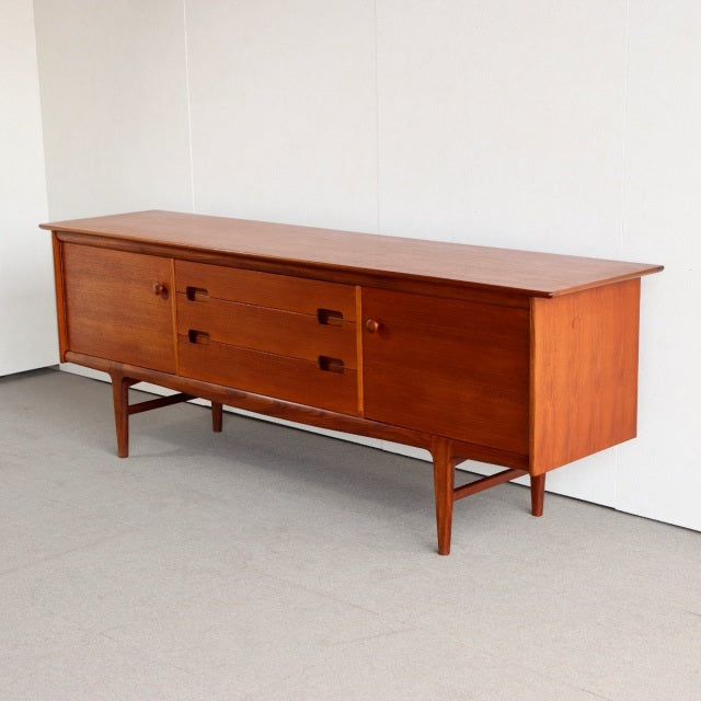 Vintage mid-century teak sideboard by YOUNGER, British design with sleek wood grain, four drawers, and tapered legs from.
